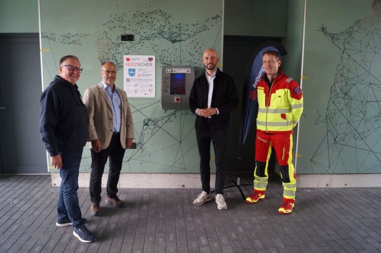 Drei Männer nehmen einen Defibrillator am Spreewald Stadion in Betrieb