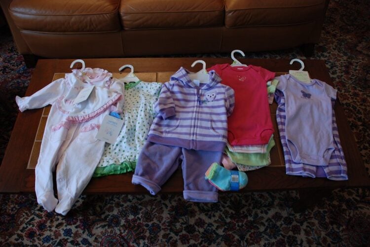 Neue Babykleidung mit Preisschildern liegt auf einem Tisch ausgebreitet