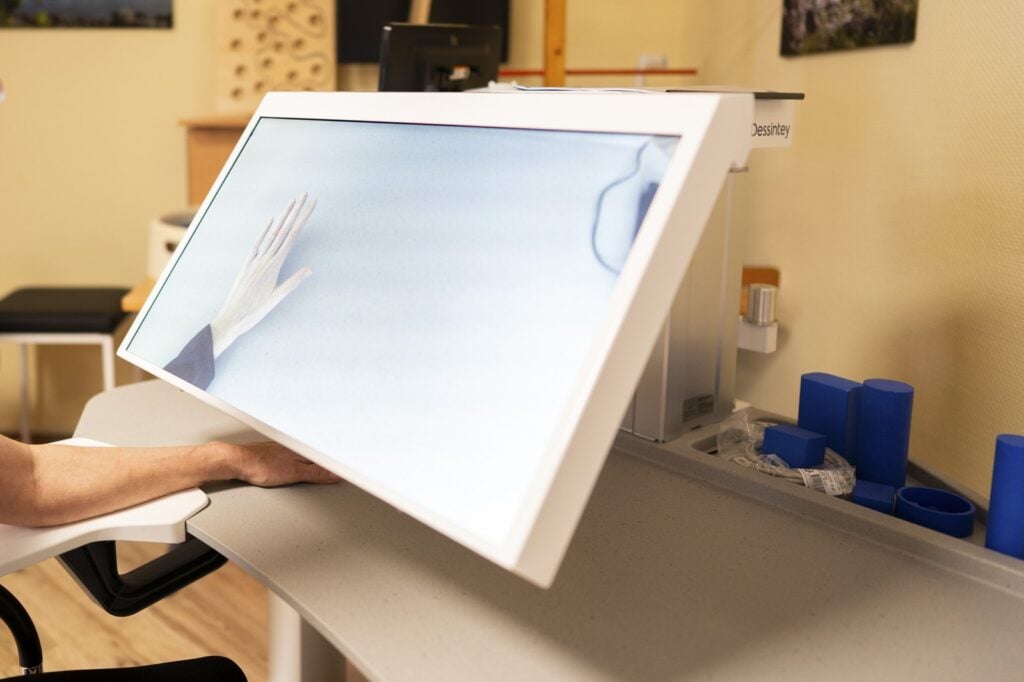 Bildschirm eines Therapiegeräts zeigt eine gespiegelte Hand