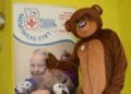 Bär im Kostüm steht neben dem Banner der Teddy-Klinik