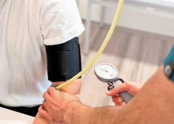 Blutdruckmessung am Oberarm eines Patienten in einer Arztpraxis