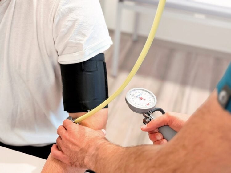 Blutdruckmessung am Oberarm eines Patienten in einer Arztpraxis