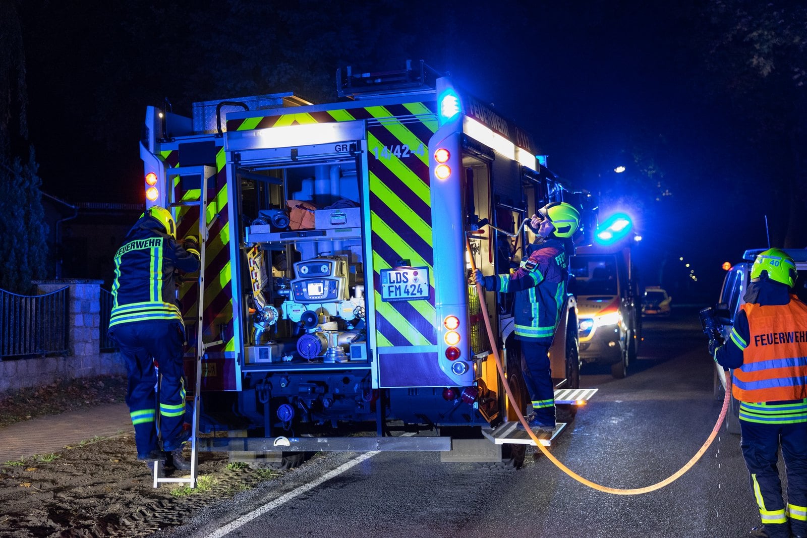 Feuerwehrleute an einem Einsatzfahrzeug in Motzen bei Nacht