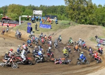 Motocross-Fahrer beschleunigen nach dem Start durch die erste Kurve