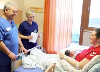 Chefarzt Maher El-Kaissi und Familienhebamme Beatrice Handschack am Bett einer jungen Mutter mit Baby