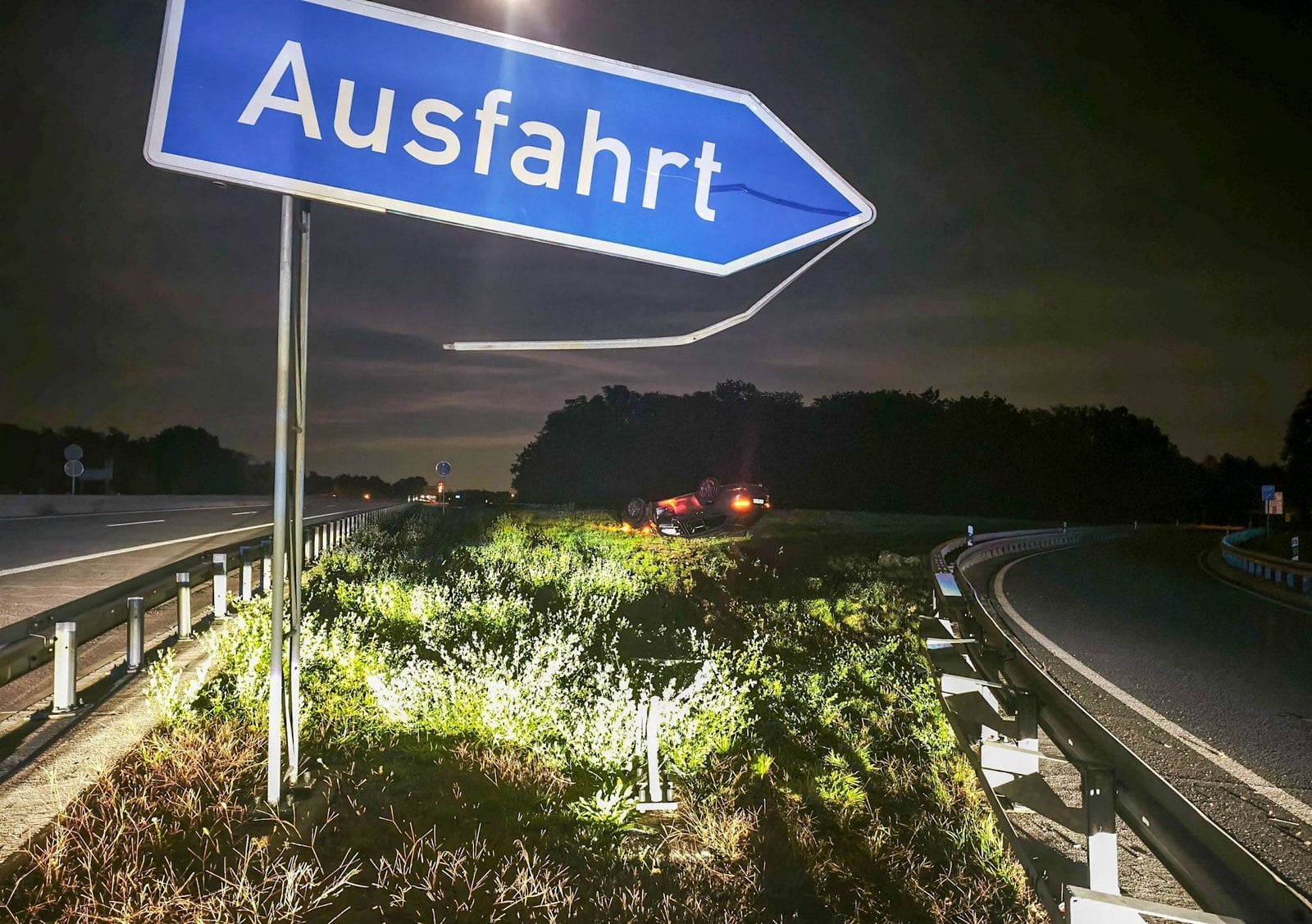 Ausfahrtschild an der A15, im Hintergrund der Unfallwagen auf der Mittelinsel