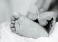 Symbolbild Sternenkinder, schwarz-weiße Nahaufnahme eines Babyfußes neben einem Stoffschmetterling