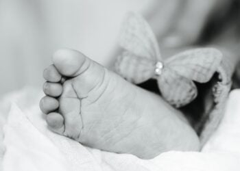 Symbolbild Sternenkinder, schwarz-weiße Nahaufnahme eines Babyfußes neben einem Stoffschmetterling