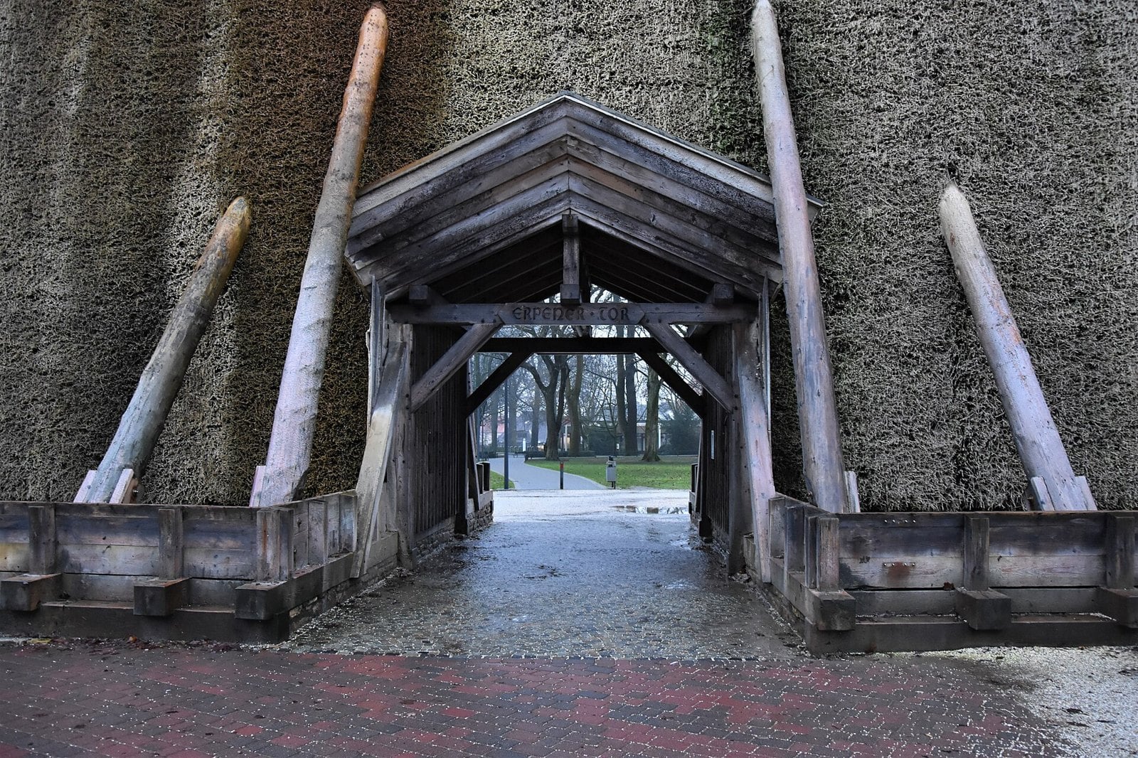 Durchgang durch ein hohes, mit Reisig bedecktes Gradierwerk in Bad Rothenfelde, überdacht von einem Holztor mit der Aufschrift Erpener Tor