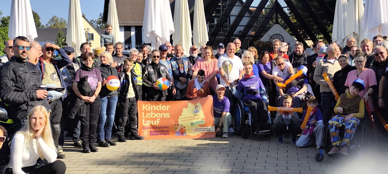 Kinder-Lebens-Lauf Burg: Biker, Familien und Mitarbeitende des Kinderhauses Pusteblume mit dem Banner der Kampagne