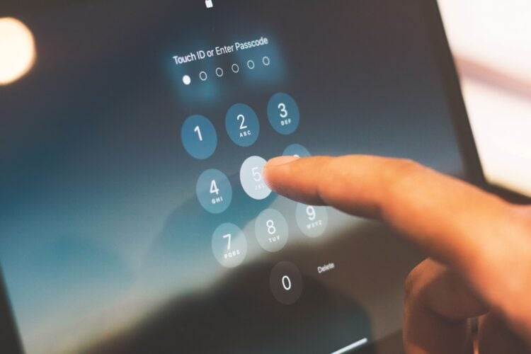 Ein Finger tippt auf einem Tablet-Bildschirm einen Zahlencode zur Entsperrung ein