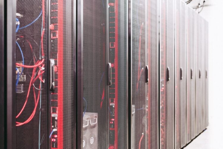 Reihe schwarzer Serverschränke in einem Rechenzentrum, davor rote und blaue Netzwerkkabel