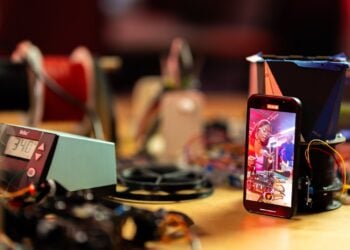Smartphone auf einer Werkbank filmt eine Person bei der Arbeit