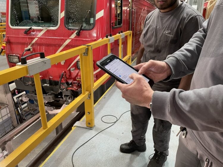 Zwei Techniker mit Tablet vor einem Triebfahrzeug in der Werkstatt