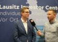 Andreas Schwerin vom Lausitz Investor Center im Interview vor einer Werbewand des Centers