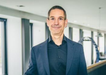 Ralph Möhler in dunklem Sakko und schwarzem Hemd in einem hellen Gebäude