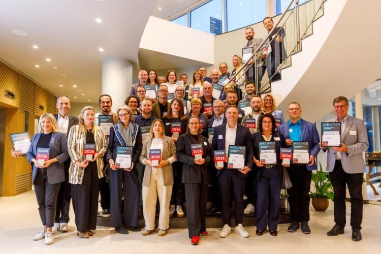 Gruppenfoto der ausgezeichneten Arbeitgeber mit Urkunden und Pokalen auf einer Treppe