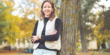 Porträt von Prof. Dr. Cordula Endter, an einen Baum gelehnt im Herbstlaub
