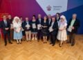Gruppenfoto der Geehrten mit Urkunden, zwei Frauen in sorbischer Tracht, vor einer Wand mit Domowina-Logo