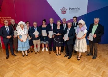 Gruppenfoto der Geehrten mit Urkunden, zwei Frauen in sorbischer Tracht, vor einer Wand mit Domowina-Logo