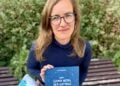 Lea Sattler sitzt auf einer Bank und hält das Buch Das Grand Hotel der Gefühle