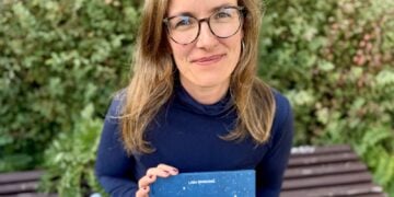 Lea Sattler sitzt auf einer Bank und hält das Buch Das Grand Hotel der Gefühle