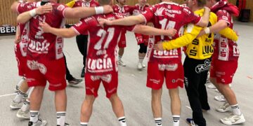 Die Handballer des LHC Cottbus stehen nach dem Sieg in Altlandsberg Arm in Arm im Kreis in der Halle