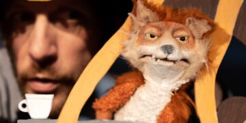 Puppenspieler im Hintergrund, im Vordergrund eine Fuchs-Handpuppe in einer Bühnenkulisse