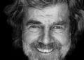 Schwarz-Weiß-Porträt von Reinhold Messner mit grauem Bart und lockigem Haar, lachend