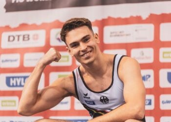 Ein Turner des deutschen Teams posiert beim Trampolin-Weltcup in Cottbus vor der Sponsorenwand