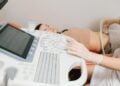 Ärztin führt bei einer liegenden Patientin eine Ultraschalluntersuchung des Bauchs durch