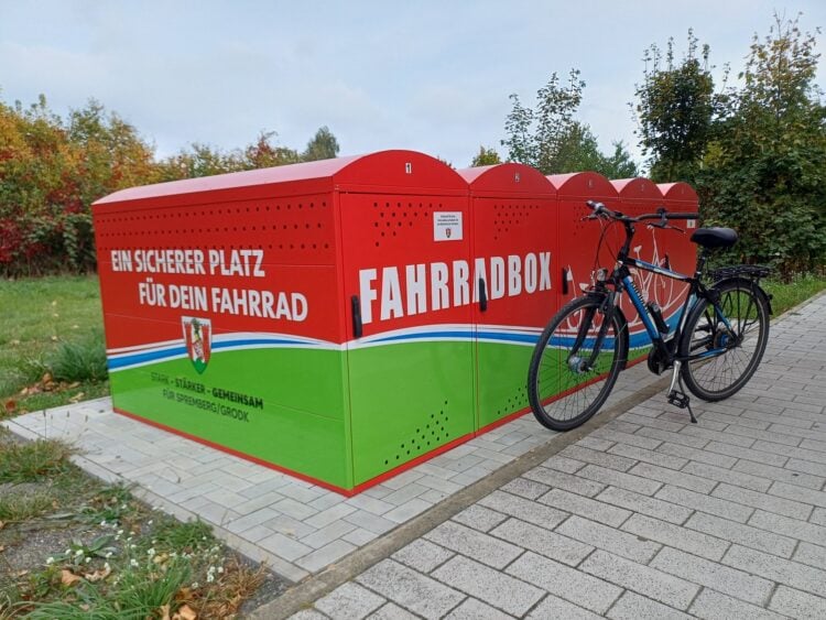 Fünf rote Fahrradboxen am Egon-Wochatz-Platz in Spremberg, davor ein abgestelltes Fahrrad