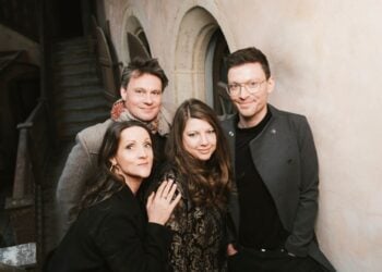 Die vier Musiker von Christmas 4 Friends, zwei Frauen und zwei Männer, vor einer hellen Wand