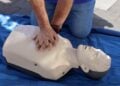 Zwei Hände drücken bei einer Herzdruckmassage auf den Brustkorb einer Übungspuppe