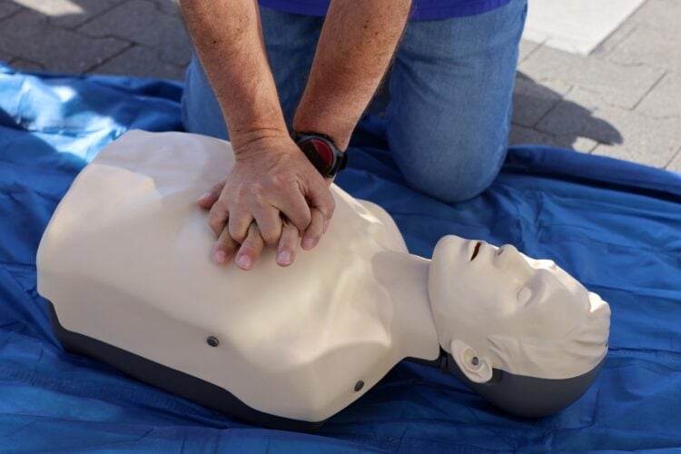 Zwei Hände drücken bei einer Herzdruckmassage auf den Brustkorb einer Übungspuppe