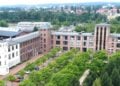 Luftbild von Guben mit einem langgestreckten Backsteinbau, Bäumen und Dächern der Stadt