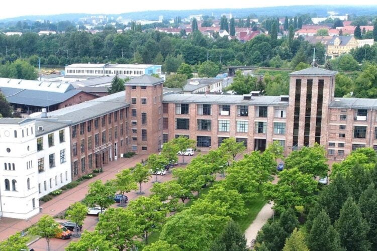 Luftbild von Guben mit einem langgestreckten Backsteinbau, Bäumen und Dächern der Stadt
