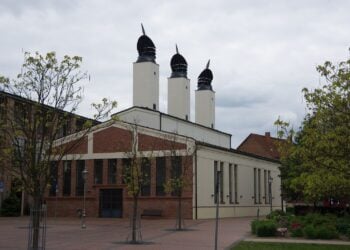 Backsteinbau mit drei weißen Türmen und dunklen Hauben auf dem Gelände der ehemaligen Hutfabrik Wilke in Guben