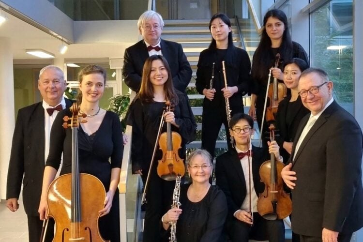 Musikerinnen und Musiker des Brandenburgischen Konzertorchesters Eberswalde mit Cello, Violinen, Flöte und Klarinette auf einer Treppe