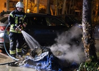 Feuerwehrmann löscht die Reste einer ausgebrannten Tonne in Königs Wusterhausen