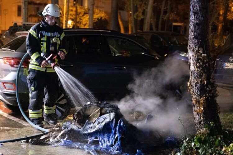 Feuerwehrmann löscht die Reste einer ausgebrannten Tonne in Königs Wusterhausen