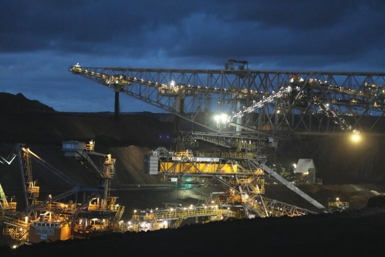 Beleuchtete Förderbrücke und Großgeräte im Tagebau Welzow-Süd in der Abenddämmerung