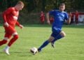 Ein Lichterfelder Spieler in Blau und ein Kostebrauer Spieler in Rot laufen zum Ball