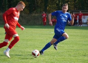 Ein Lichterfelder Spieler in Blau und ein Kostebrauer Spieler in Rot laufen zum Ball