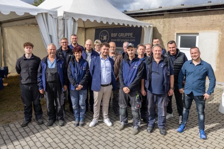 Gruppenfoto von rund 20 Mitarbeitenden der BBF Elektrotechnik vor einem Zelt mit der Aufschrift BBF Gruppe