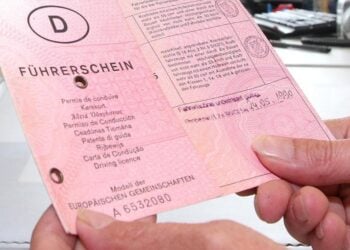 Zwei Hände halten einen alten rosafarbenen Papierführerschein