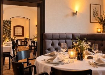 KI-bearbeitetes Bild eines gedeckten Restaurant-Gastraums mit Kerzen, Weingläsern und Polsterbank