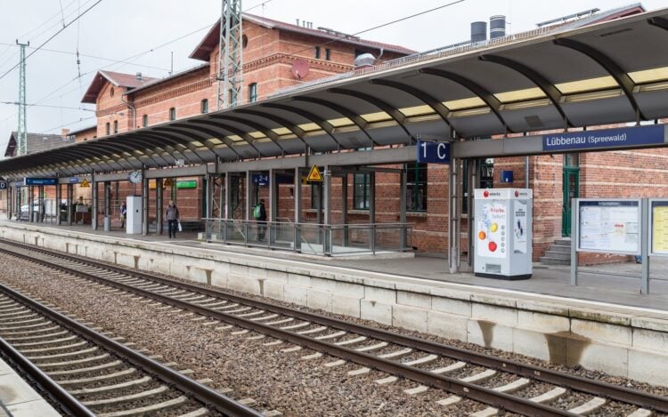 Bahnsteig und Gleise am Bahnhof Lübbenau (Spreewald), dahinter das Empfangsgebäude aus Backstein