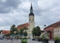 Kirchplatz in Lübbenau mit der Nikolaikirche und Häusern der Altstadt unter bewölktem Himmel