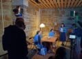Jugendliche in blauen Kostümen spielen an einem Tisch in einem Raum mit Sandsteinwänden, im Vordergrund Tonangel, Scheinwerfer und Kameramonitor